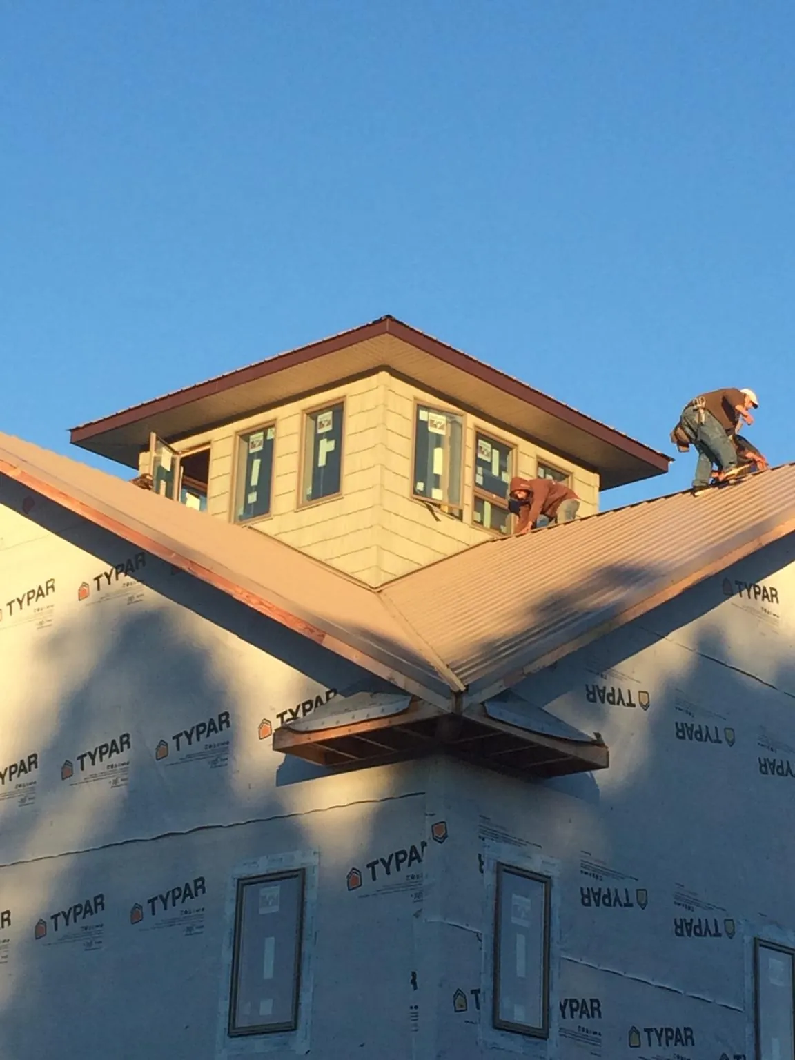 Roofers working around a rooftop cupola on a new metal roof at sunset — Roof Waterproofing in Fayetteville by Roofing Brothers